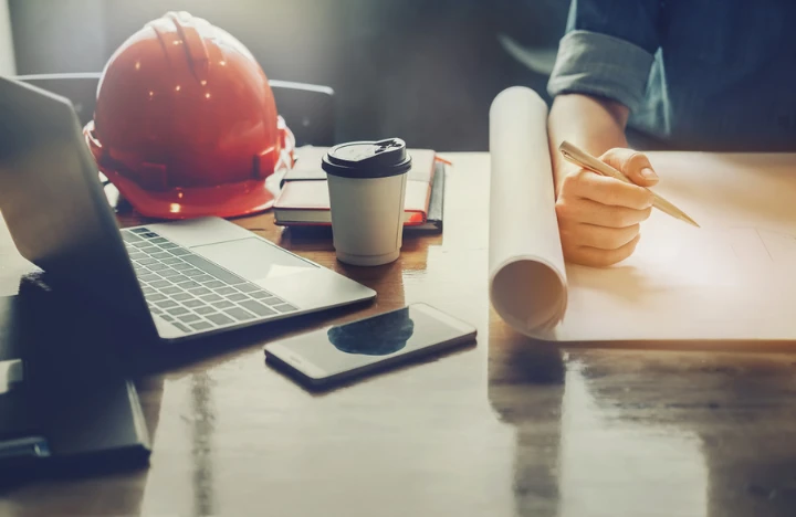 Laptop on top of desk next to construction hat