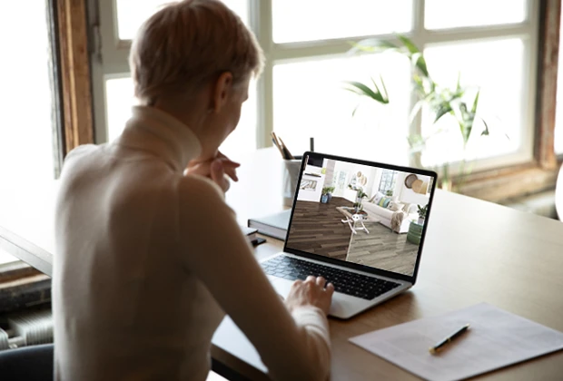 A person looking at a laptop with a picture comparing different floors