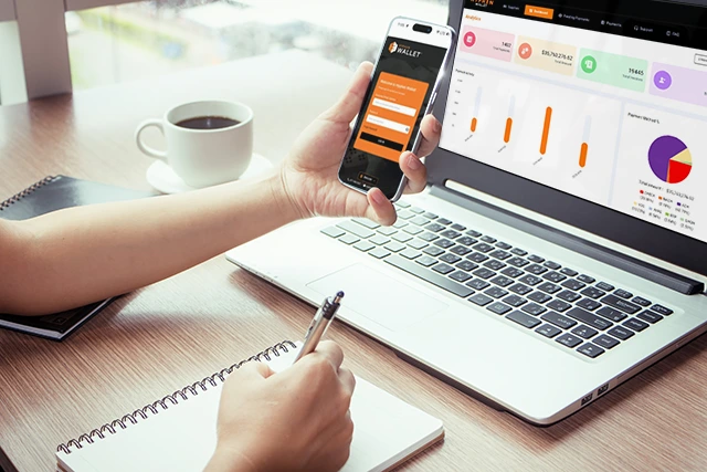 Person holding phone by laptop with Hyphen Wallet dashboard open