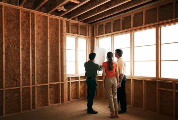 Three people looking over plans inside a new construction site