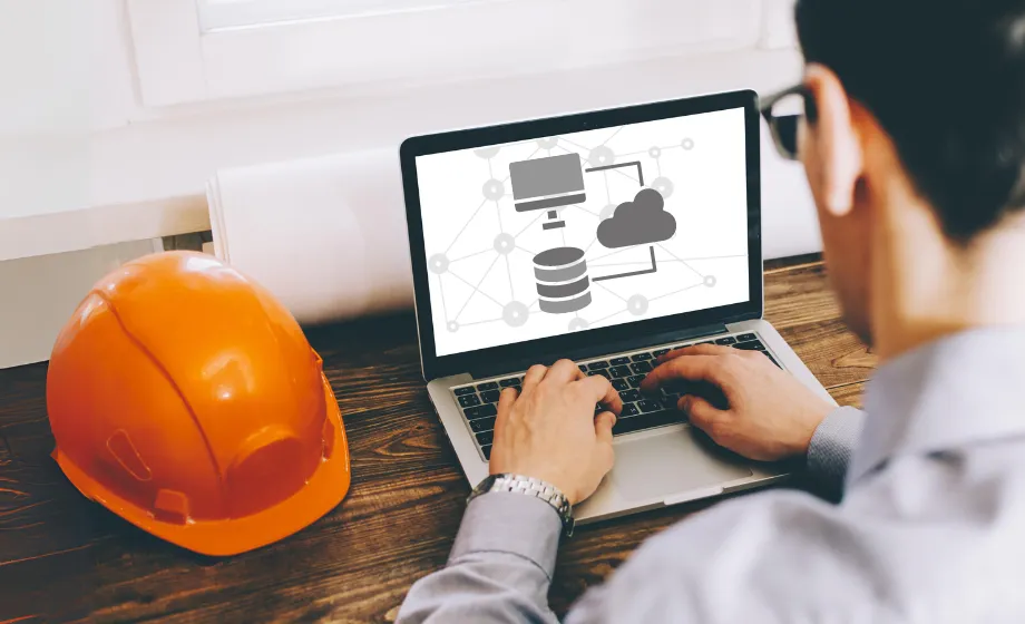 Man on a laptop in front of a construction hat