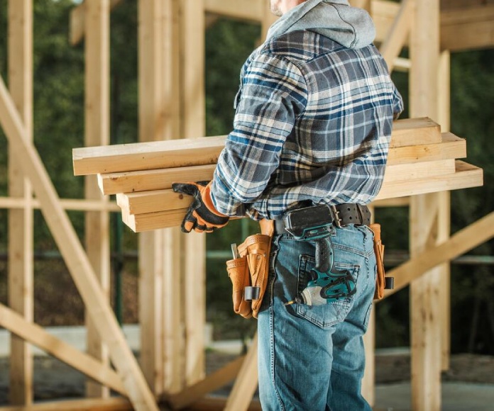 construction worker holding lumber at new build site
