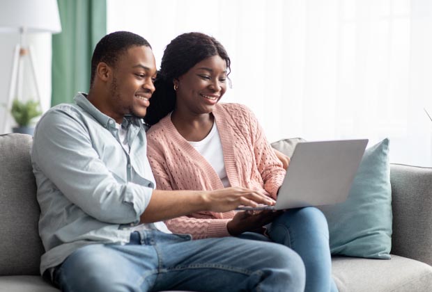 Couple smiling holding a laptop