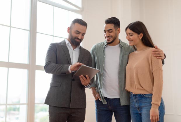 couple standing in front of a man showing them something on a tablet