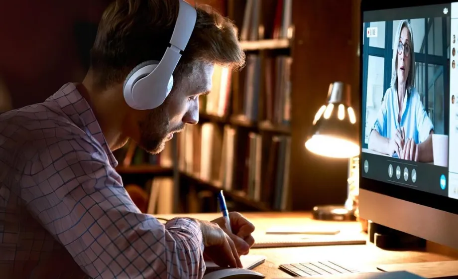 Man with headphones writing in a journal