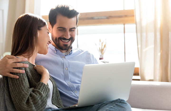 A couple smiling in front of a laptop