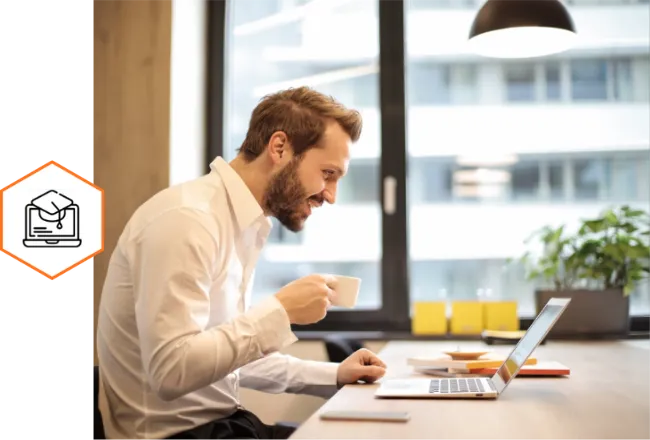 Man on a laptop holding a coffee