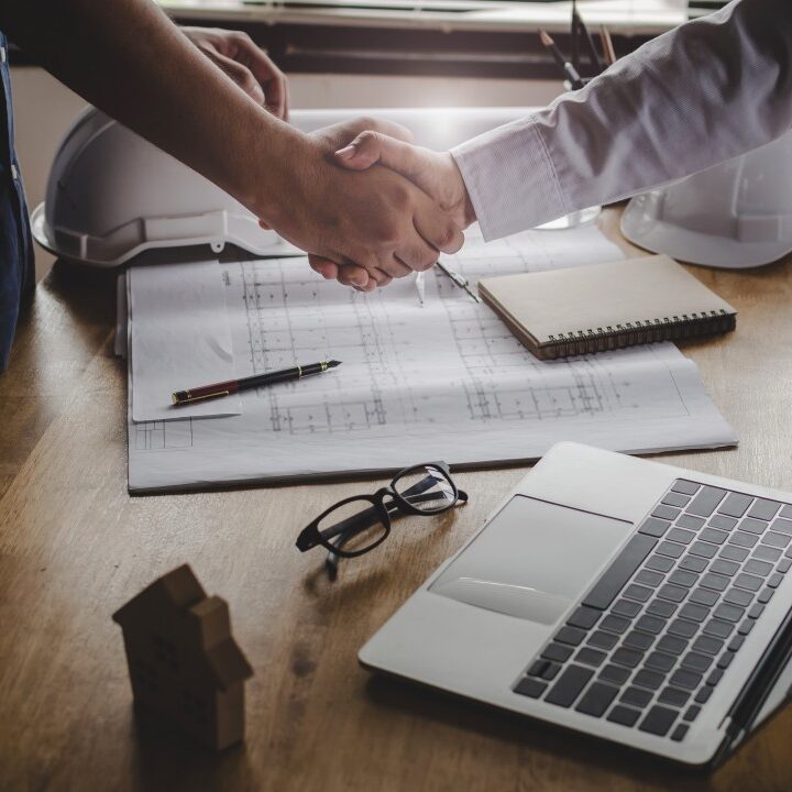 Two men shaking hands with Hyphen paperwork on the desk