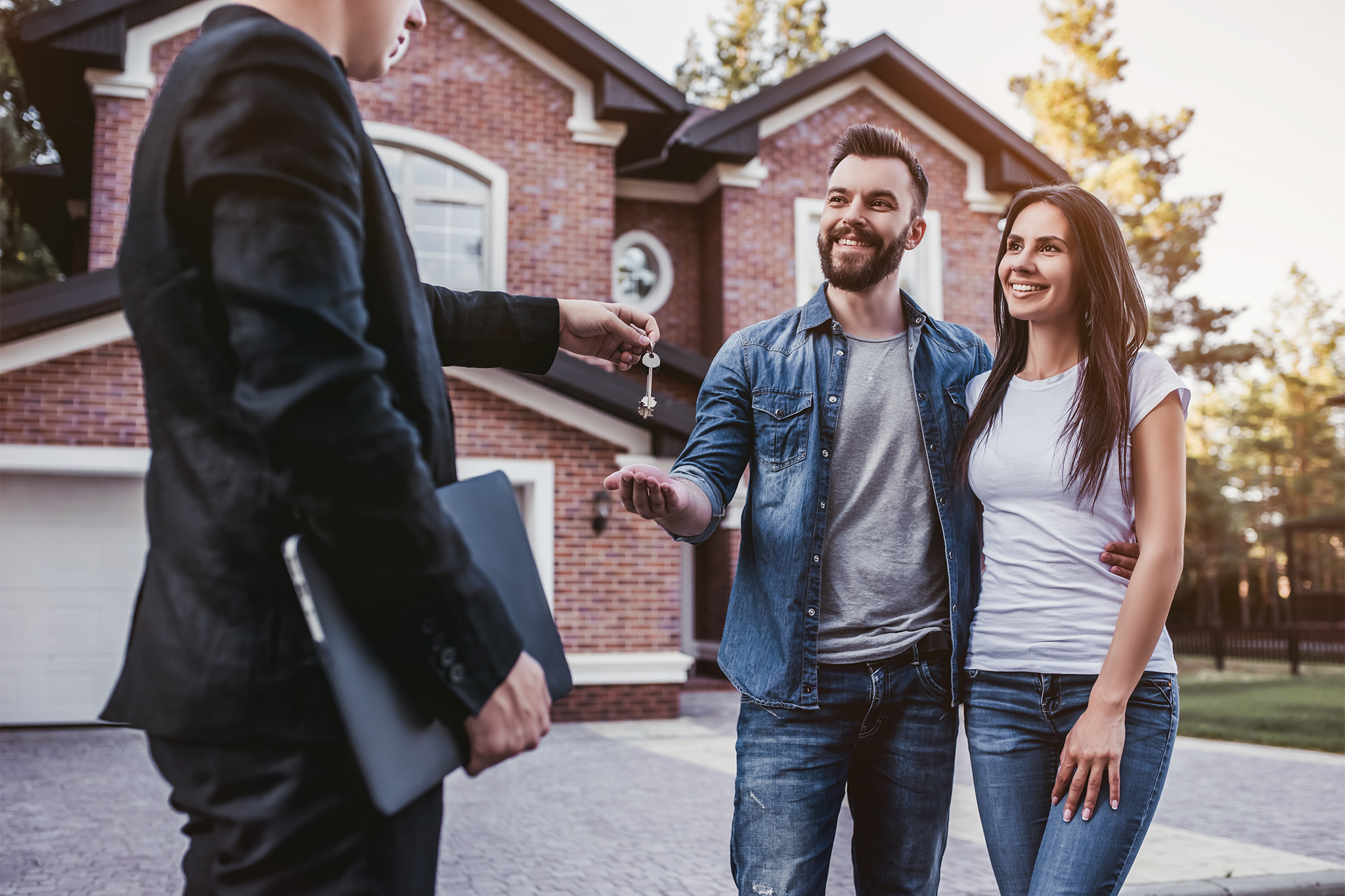 Happy couple is taking keys from their new house from broker and smiling.