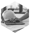 Hand on a laptop keyboard with a hard hat on the desk